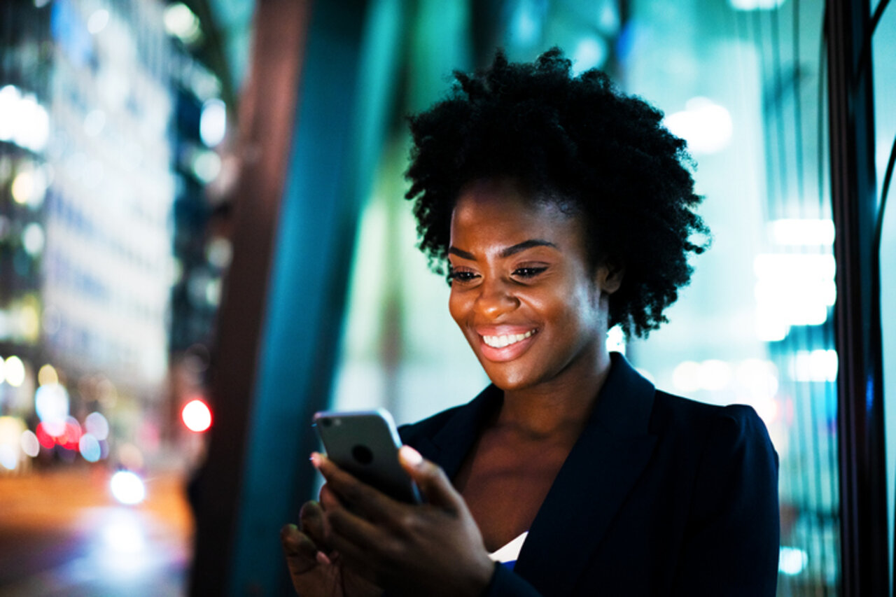 Woman using smart phone at night and smiling | © GettyImages