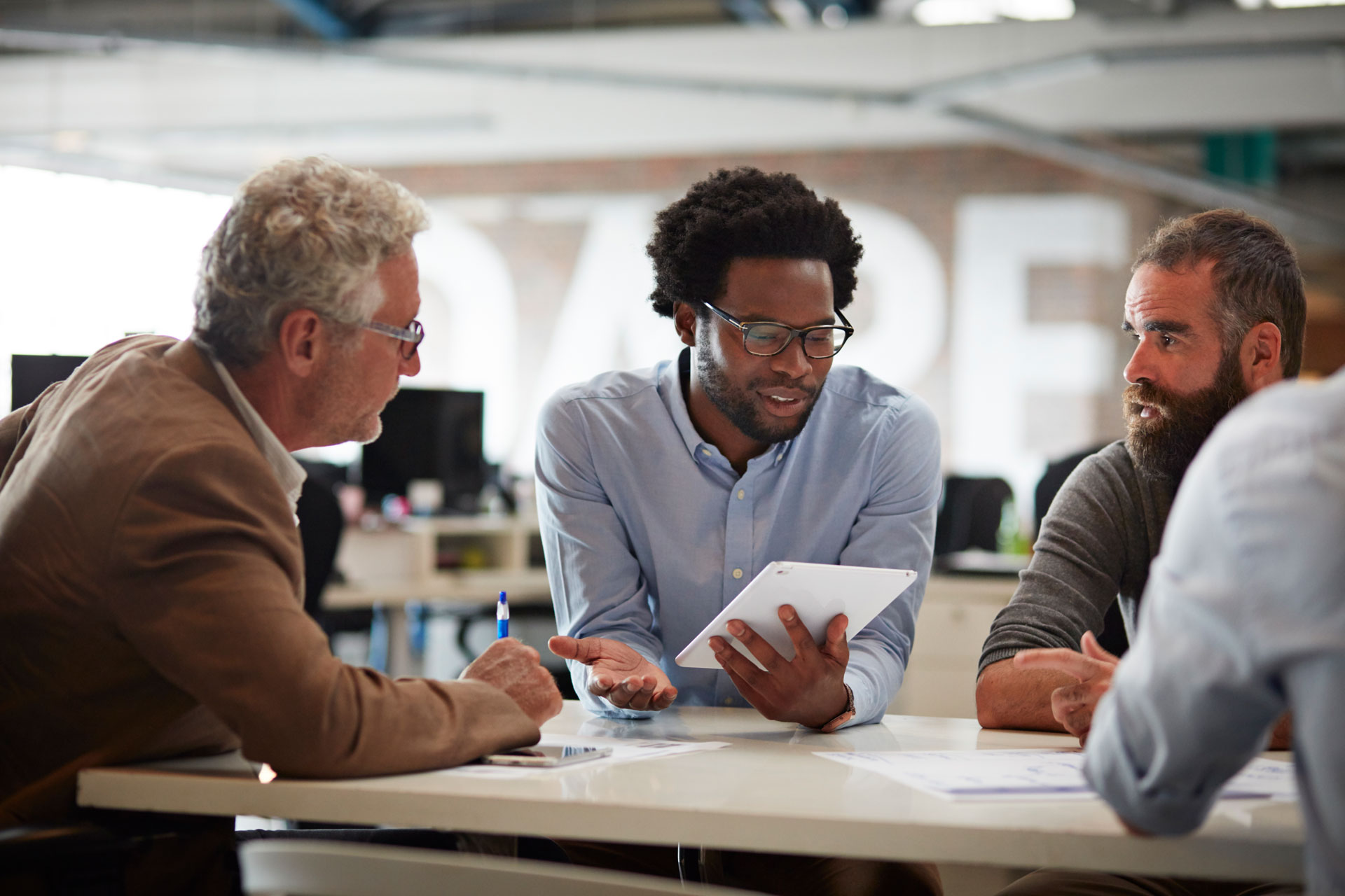 Businesspeople at big creative agency.Businessman presenting to co-workers with tablet