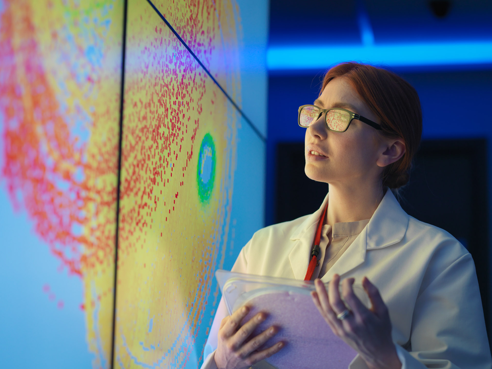 Young woman with glasses looking at a big colorful screen | © Monty Rakusen's Studio