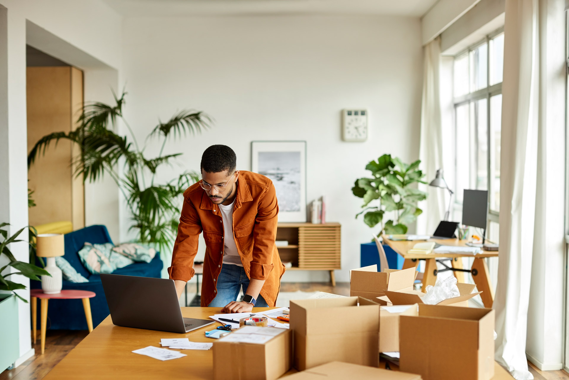 Young male freelancer leaning by packages on table in home office.  | © Morsa Images @GettyImages
