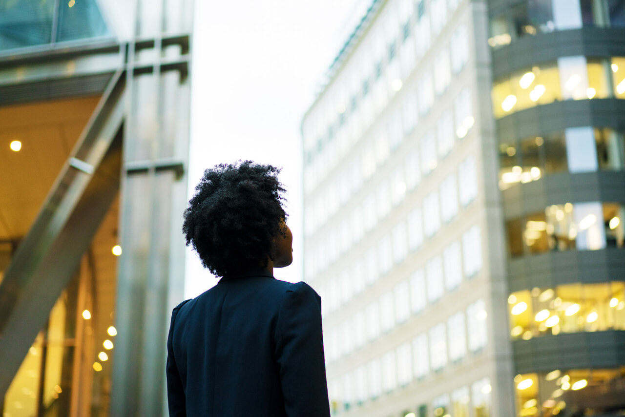 Woman looking up at office buildings | © Tim Robberts @GettyImages