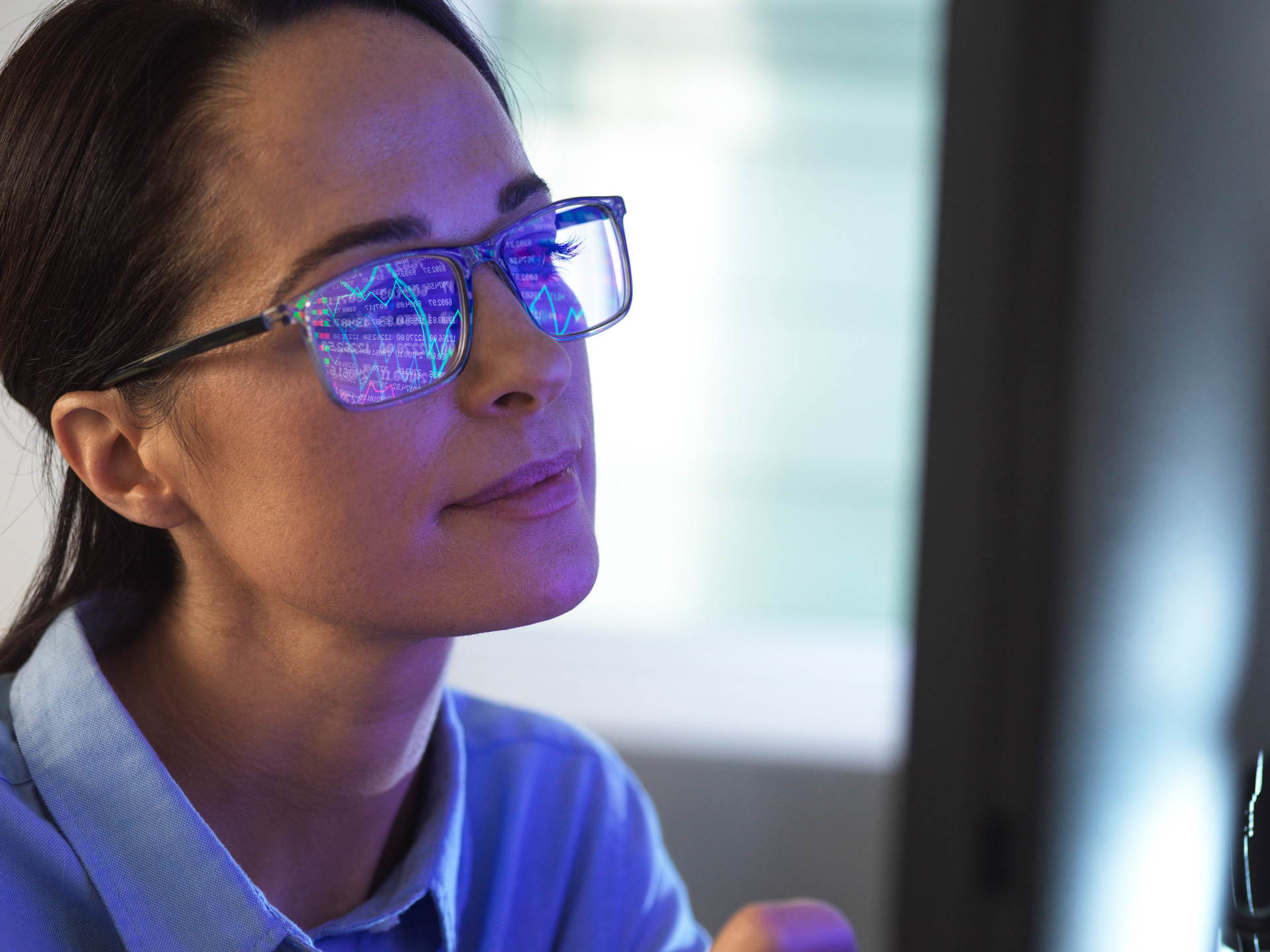 Female expert in glasses looking at screen with financial data