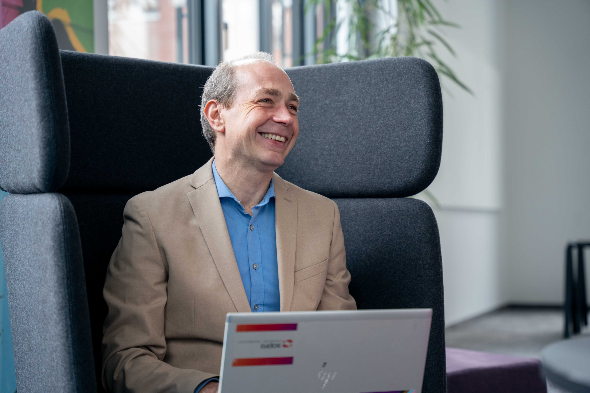 Sopra employee smiling and working on a laptop